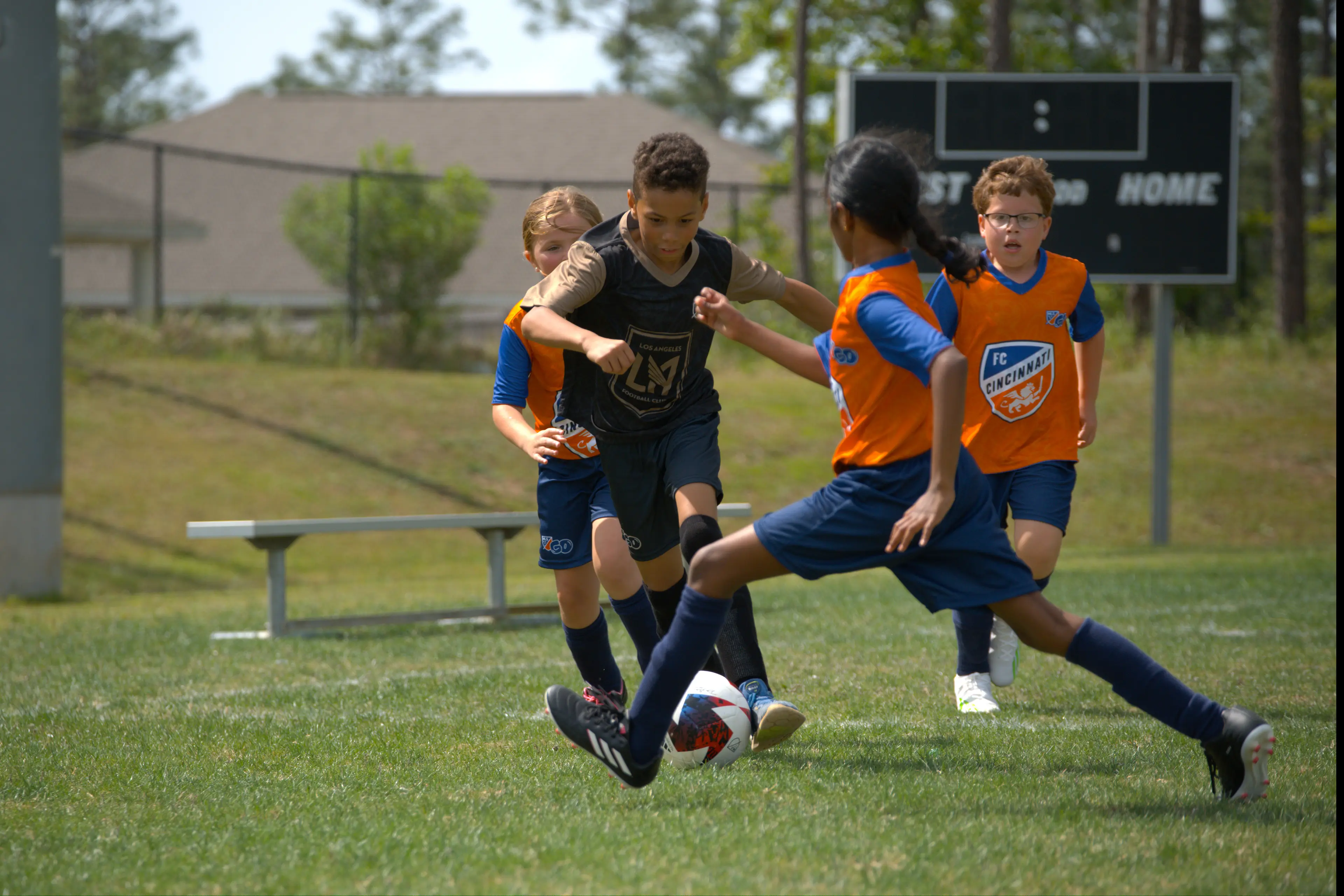 Girls and boys playing soccer in official MLS GO uniforms on a green field