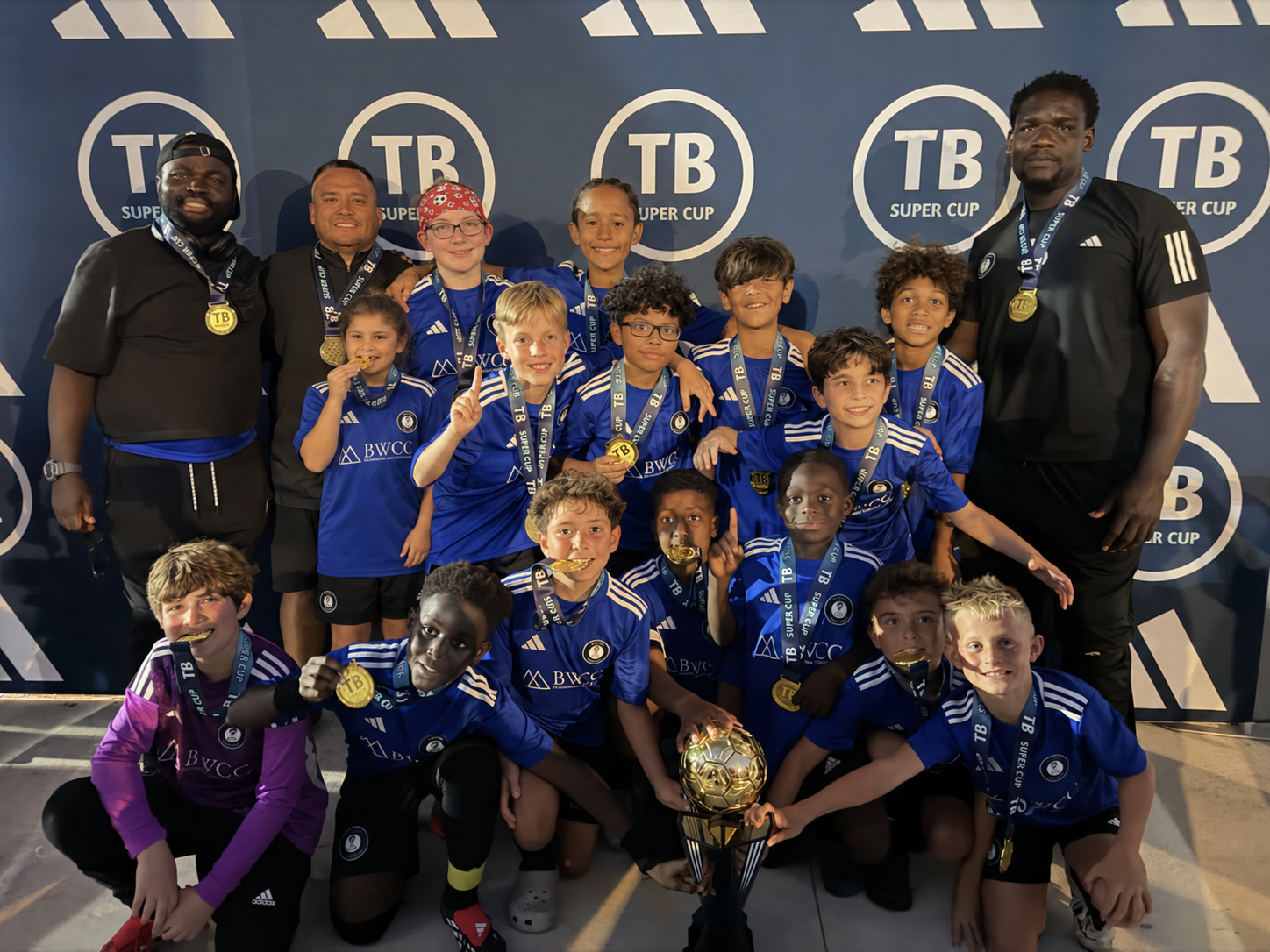 LASE LIONS U11 players and coaches celebrating their 2026 Tampa Bay Super Cup win with medals and the trophy